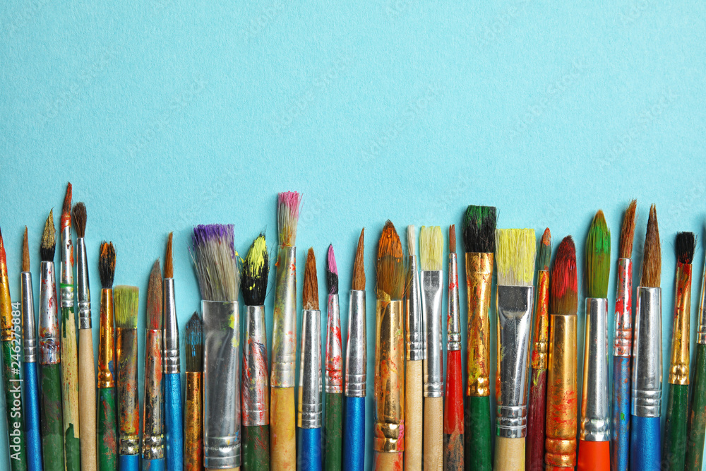 Different paint brushes on color background, top view with space for text Different paint brushes on color background, top view with space for text