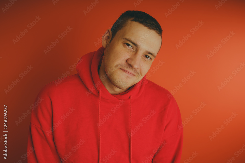 Crazy and charismatic guy posing on an orange background. A man in a red tracksuit. Crazy and charismatic guy posing on an orange background. A man in a red tracksuit.