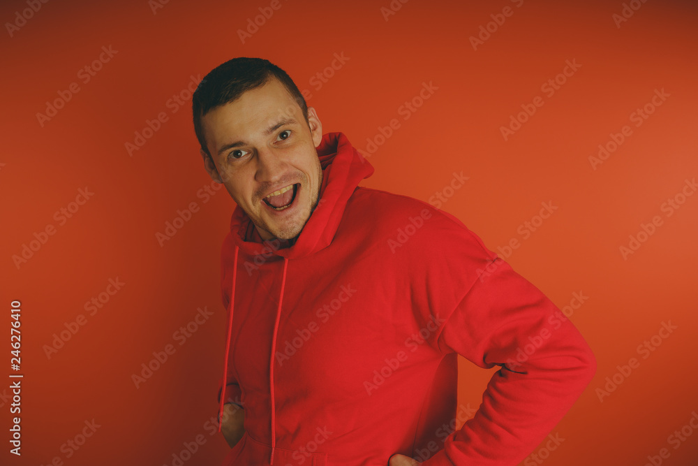 Crazy and charismatic guy posing on an orange background. A man in a red tracksuit. Crazy and charismatic guy posing on an orange background. A man in a red tracksuit.