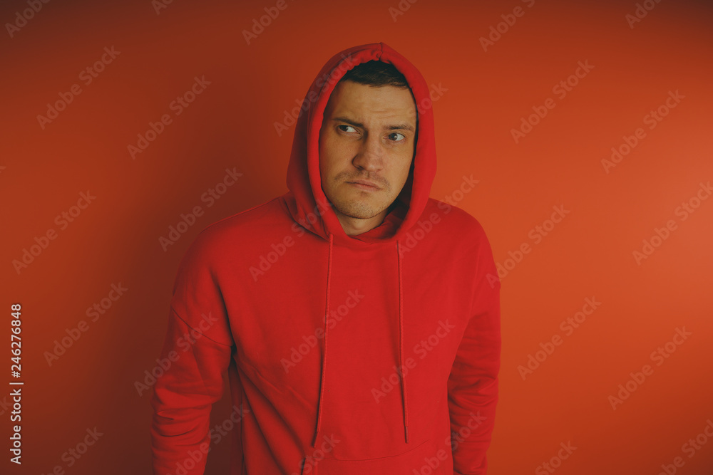 Crazy and charismatic guy posing on an orange background. A man in a red tracksuit. Crazy and charismatic guy posing on an orange background. A man in a red tracksuit.