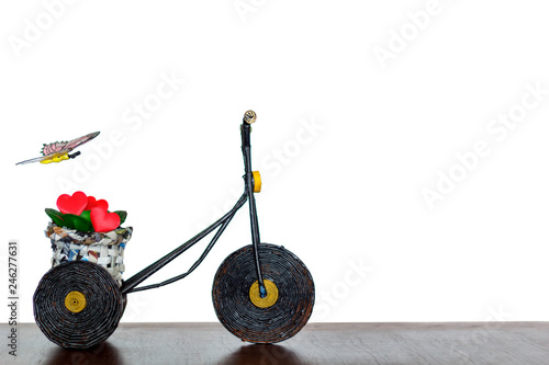 Bicycle with plant and red hearts in basket and a butterfly flying. Love and Valentine's day concept