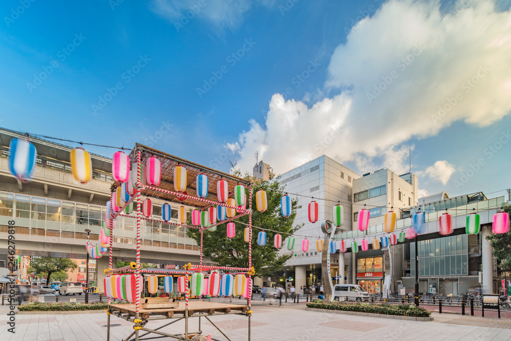 View of the square in front of the Nippori train station decorated for the Obon festival in the summer with a yagura tower and paper lanterns in the Arakawa district of Tokyo - obrazy, fototapety, plakaty 