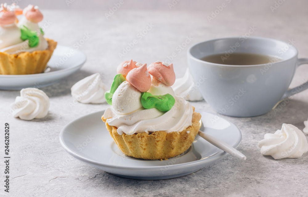 Delicious funny tartlets with meringue for kids on a light blue plate.