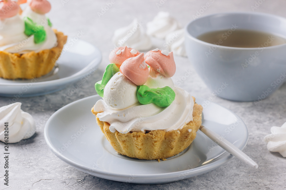 Delicious funny tartlets with meringue for kids on a light blue plate. Delicious funny tartlets with meringue for kids on a light blue plate.