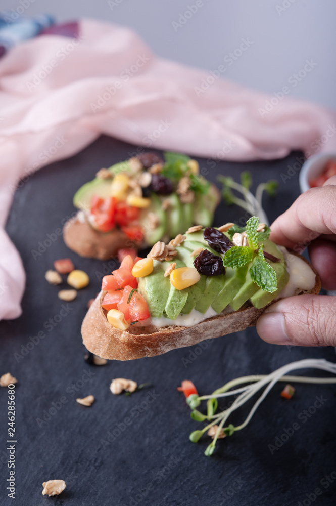 Sandwiches with avocado, tomato, corn and grains on gray board as background Sandwiches with avocado, tomato, corn and grains on gray board as background