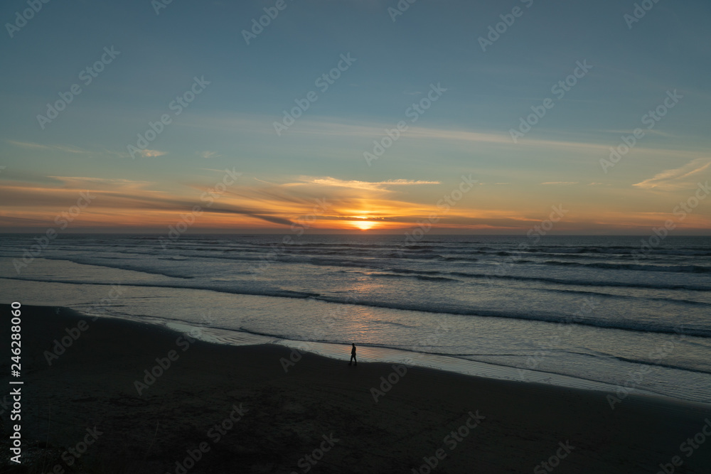 Man walking on the beach during sunset on the Oregon coast Man walking on the beach during sunset on the Oregon coast