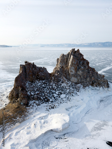 Aerial photo of Shaman rock, bay and Cape Burkhan on Olkhon island in winter. Beautiful view on frozen Baikal lake. Sunny.