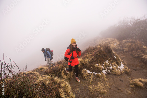Hikers couple with backpacks walking on top of mountain in fog above clouds © Annatamila
