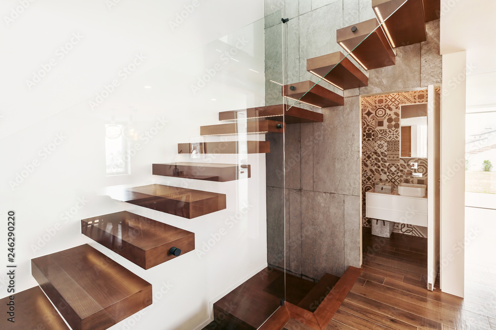 Stairs in living room with open door to bathroom and glass wall Stairs in living room with open door to bathroom and glass wall