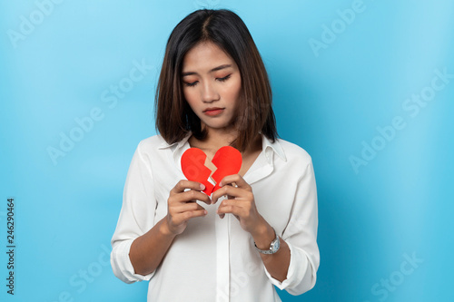 asian girl holding broken paper red heart ,valentine concept isolated on blue background