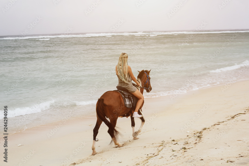 Woman wearing braids hairstyle riding horse on sea shore Woman wearing braids hairstyle riding horse on sea shore