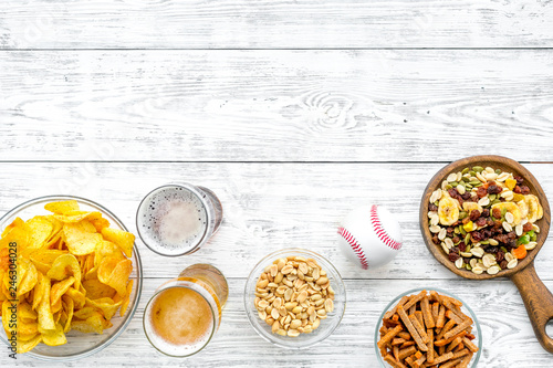 Snacks for watching american football on TV. Watching sports. Chips, nuts, rusks near beer and ball on white wooden background top view copy space