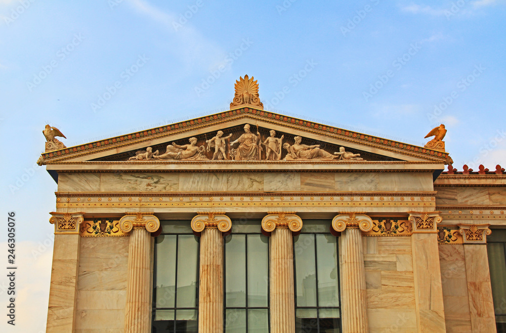 Left wing building of the National Academy of Arts in Athens, Greece with ornate details and Greek statue carvings with blue sky copy space.