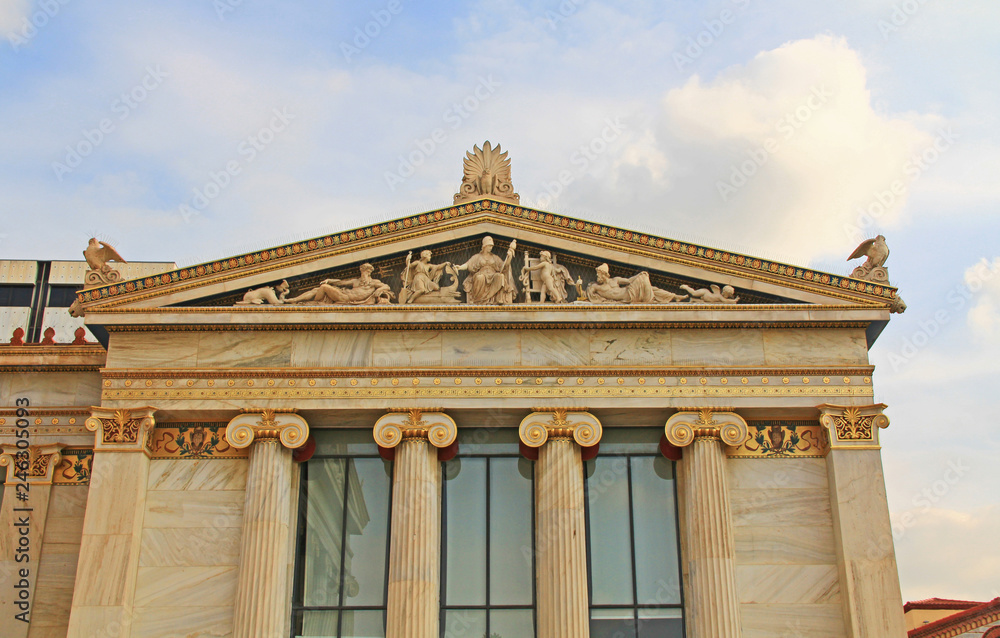 Fototapeta premium Right wing building, of the National Academy of Arts in Athens, Greece with ornate details and Greek statue carvings with blue sky copy space.