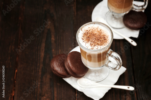 Coffee in glass on the wooden background.  A glass with cappuccino and cinnamon. 