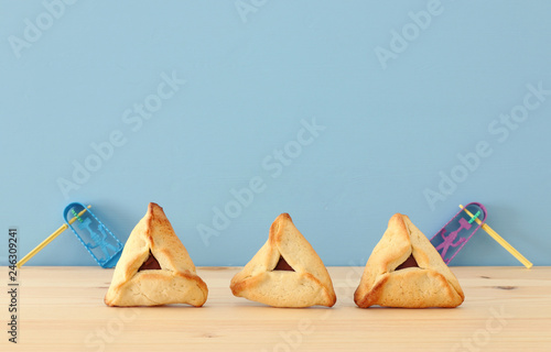 Purim celebration concept (jewish carnival holiday). Traditional hamantaschen cookies over wooden table and blue background.
