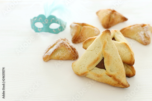 Purim celebration concept (jewish carnival holiday). Traditional hamantaschen cookies over white wooden table.