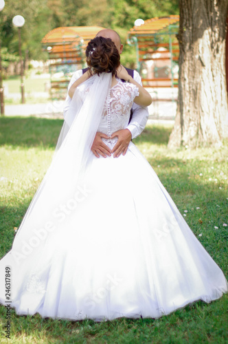 Hands of the groom in the form of a heart on the waist of the bride