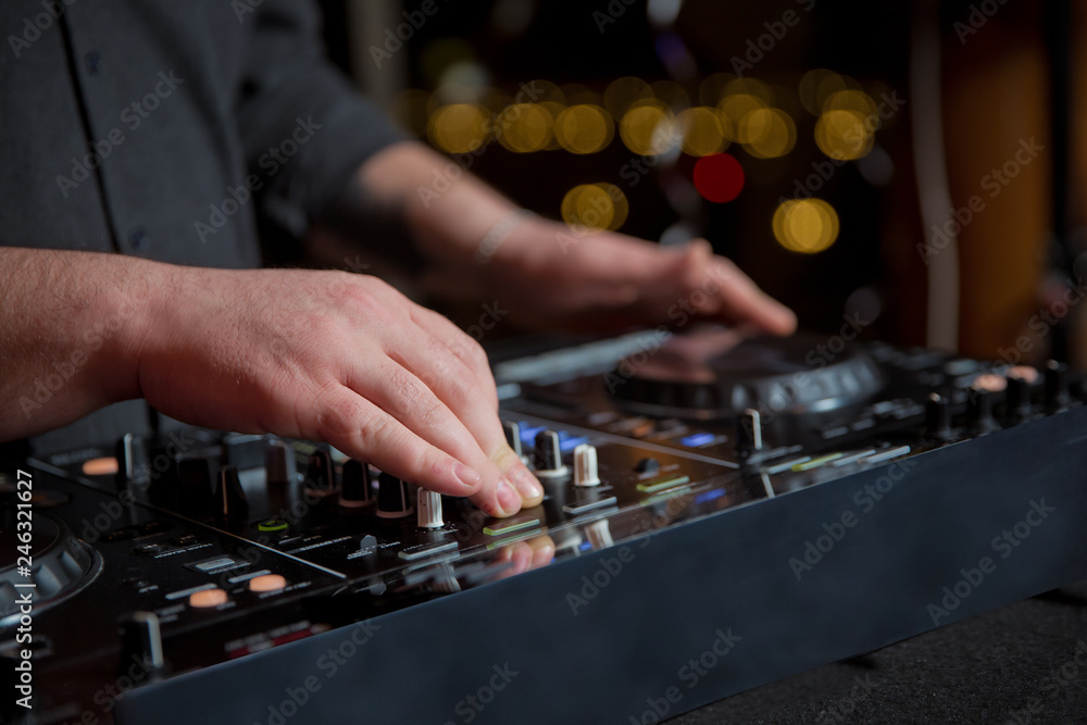Music Concepts. DJ is rhythm music with Controller and mixer. DJ is playing the song at the party. Young are adjusting the music with the controller. The fun of music and light colors.