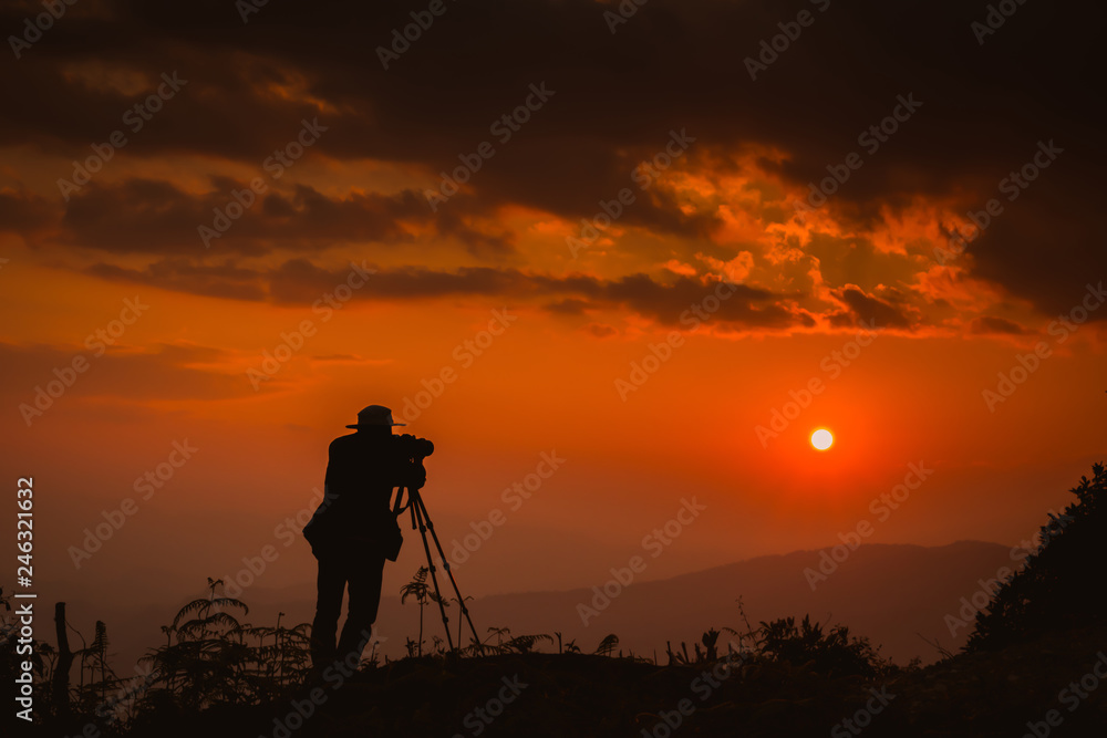 A photographer standing on top of Mountain at sunset