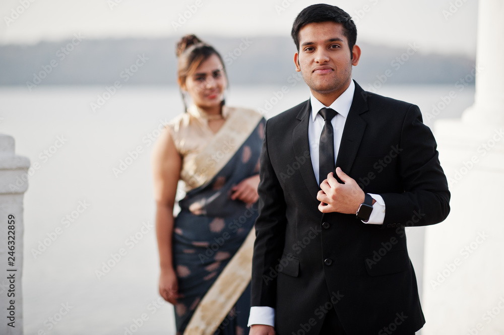 Elegant and fashionable indian friends couple of woman in saree and man in suit posed on the shore of the marina. Elegant and fashionable indian friends couple of woman in saree and man in suit posed on the shore of the marina.