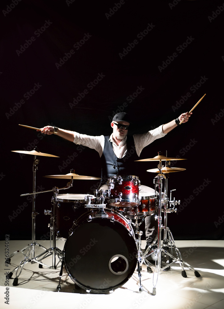 Fototapeta premium Professional drummer playing on drum set on stage on the black background