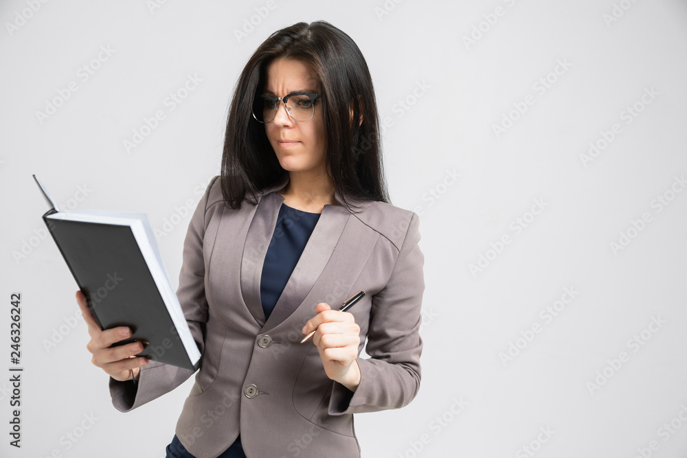 Portrait of a young girl with glasses with a diary in her hands isolated on a light background Portrait of a young girl with glasses with a diary in her hands isolated on a light background