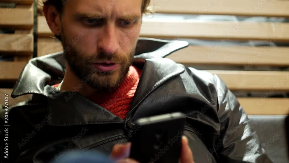 Adult brutal bearded man with mobile phone resting at cafe close-up Adult brutal bearded man with mobile phone resting at cafe close-up