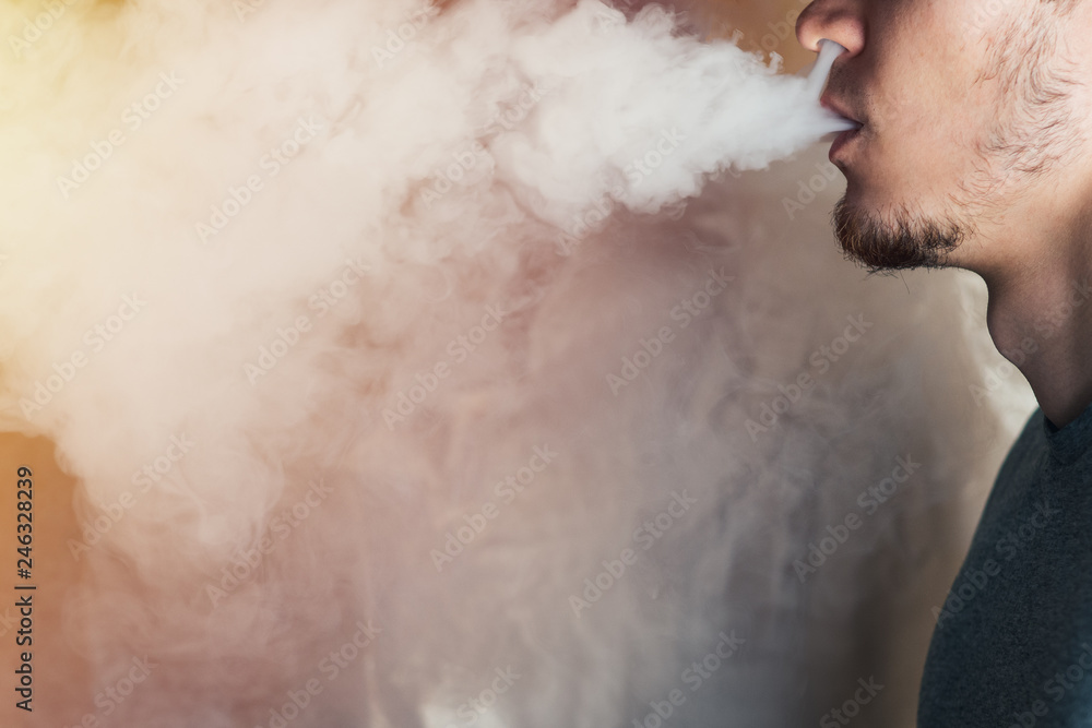 A bearded man in the clouds of steam from electronic cigarette closeup. vaping man