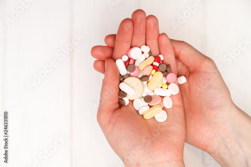 medicine in a hand on a white wooden background