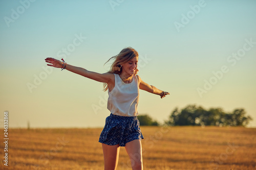 Cute young woman jumping in a wheat field.