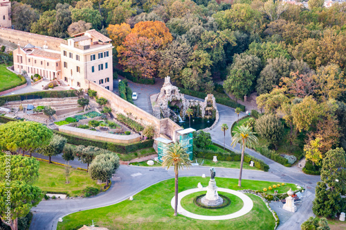 High view on cozy Vatican gardens with sculptures and fountains and museums buildings in Rome, Italy