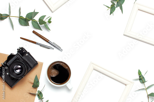 Photo frame old retro camera notebook diary cup of coffee pens eucalyptus leaves on white background. Flat lay top view copy space. Stylish minimal composition artwork mockup Feminine desk workspace