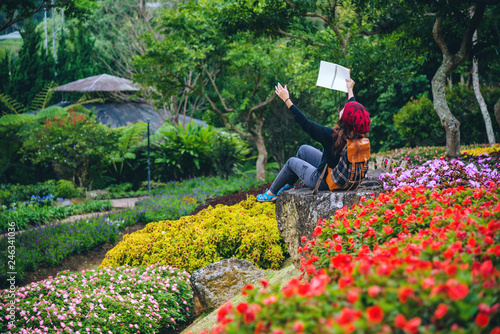 woman travel nature in the flower garden. relax sitting on rocks and reading books In the midst of nature at national park doi Inthanon...