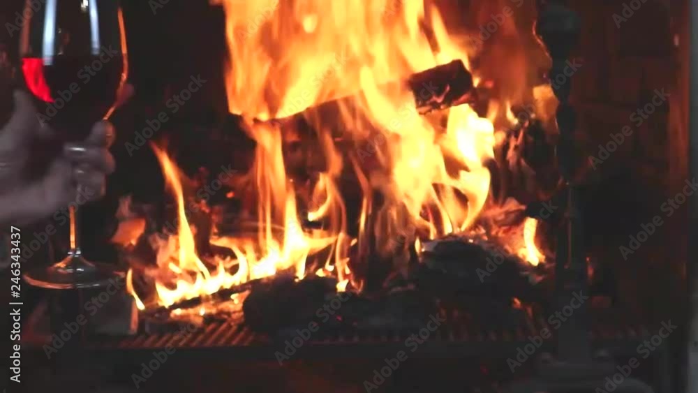 female hand holding a glass of red wine on the background of fire female hand holding a glass of red wine on the background of fire