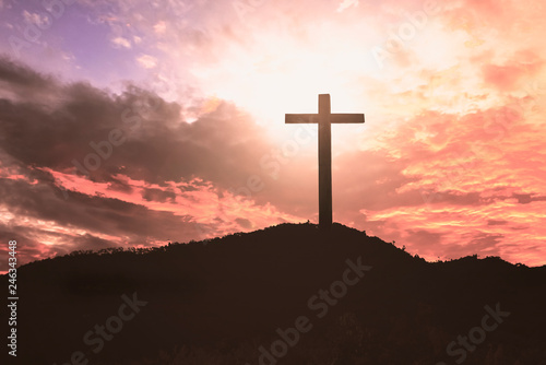  Concept of Jesus Christ: white cross on sunset sky background