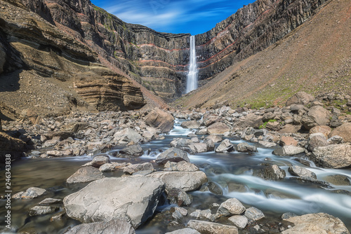 Amazing nature, scenic view of Hengifoss waterfall in Iceland falling into a magnificent gorge, colorful rock and rugged river. Icelandic summer landscape with blue sky, outdoor travel background photo