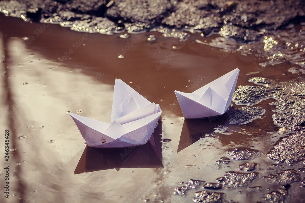 The paper boat floats through the spring puddles. Children's entertainment.