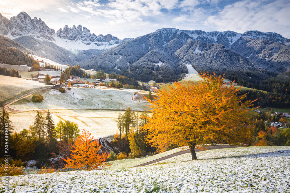 Funes valley and Santa Magdalena village during late autumn with colorful cherry trees and snow. Santa Magdalena, Funes Valley, South tyrol, Italy.
