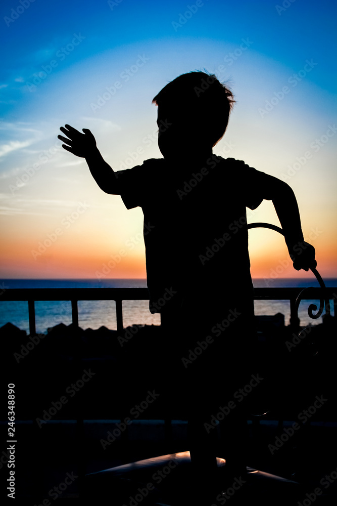 Fototapeta premium Happy child at the time of the silhouette of the sea background