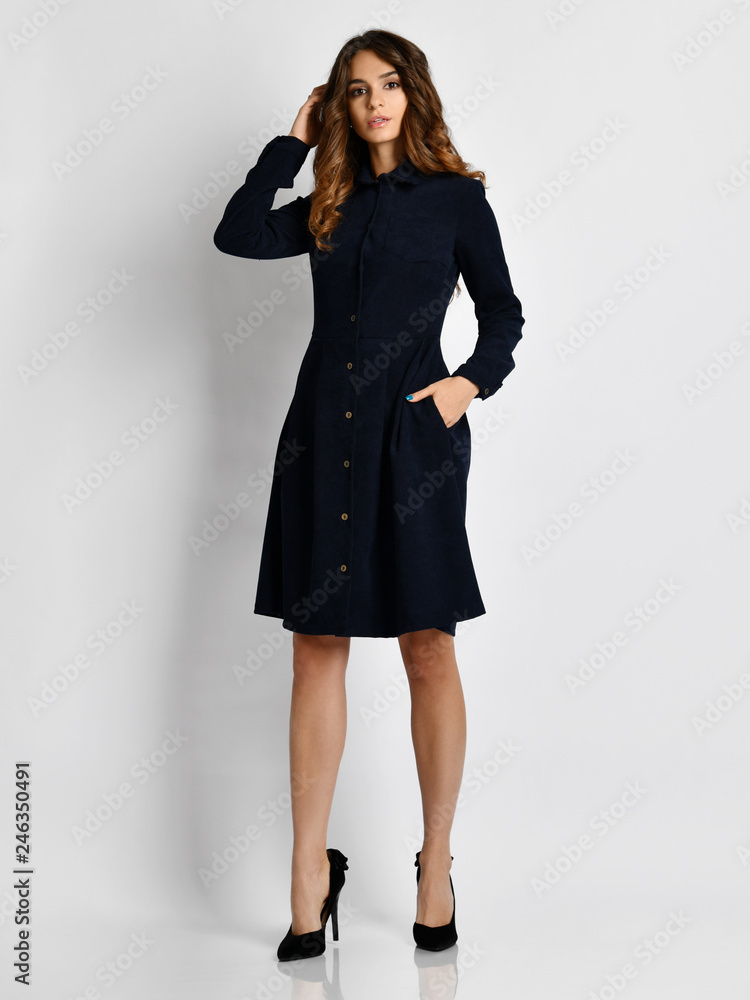 Young beautiful woman posing in new fashion dark navy blue office winter dress on a white background Young beautiful woman posing in new fashion dark navy blue office winter dress on a white background