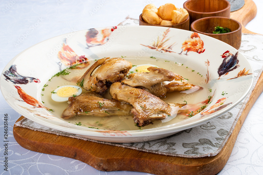 Quail broth with crackers and herbs on a wooden board. On white background. Quail broth with crackers and herbs on a wooden board. On white background.