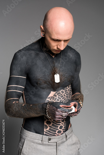 Fototapeta Naklejka Na Ścianę i Meble -  bare-chested man with tattoos holding cigarette box isolated on grey