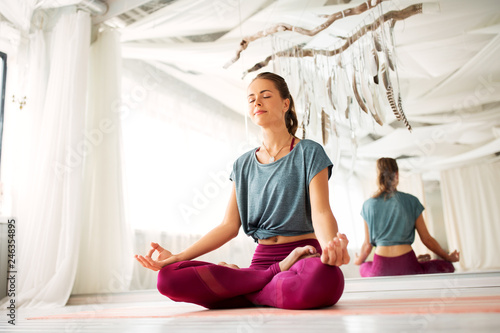 mindfulness, spirituality and healthy lifestyle concept - woman meditating in lotus pose at yoga studio