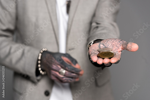 Close-up view of tattooed man holding bitcoins isolated on grey