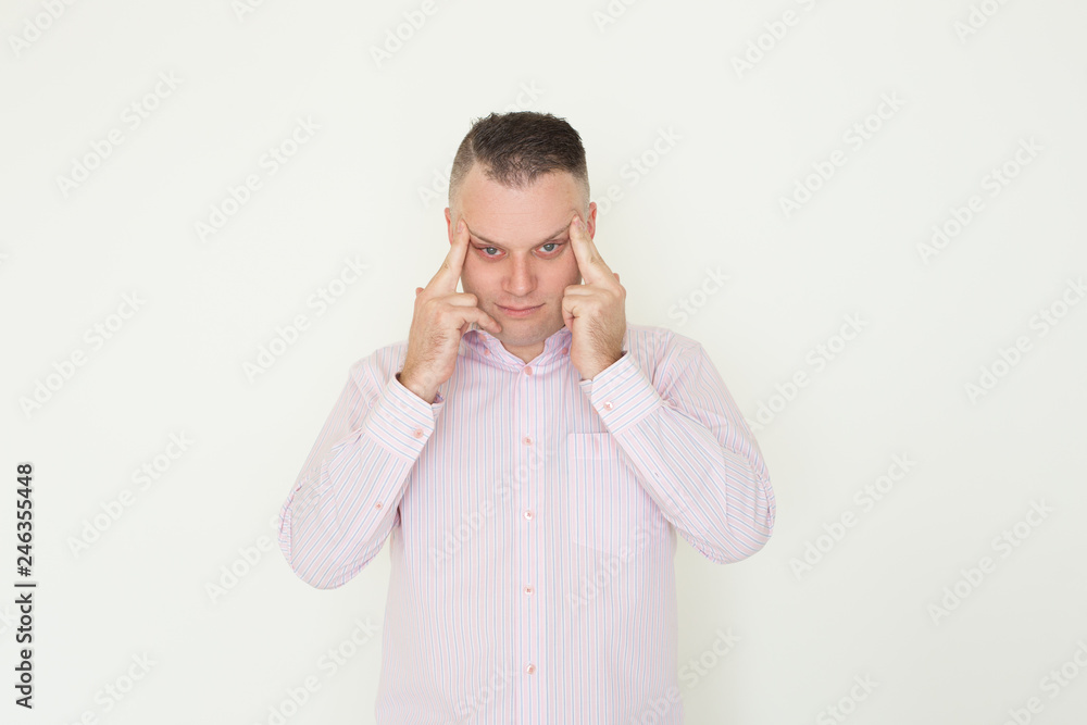 Stressed office worker thinking hard. Young Caucasian man suffering from headache and massaging temples. Head ache or stress concept Stressed office worker thinking hard. Young Caucasian man suffering from headache and massaging temples. Head ache or stress concept