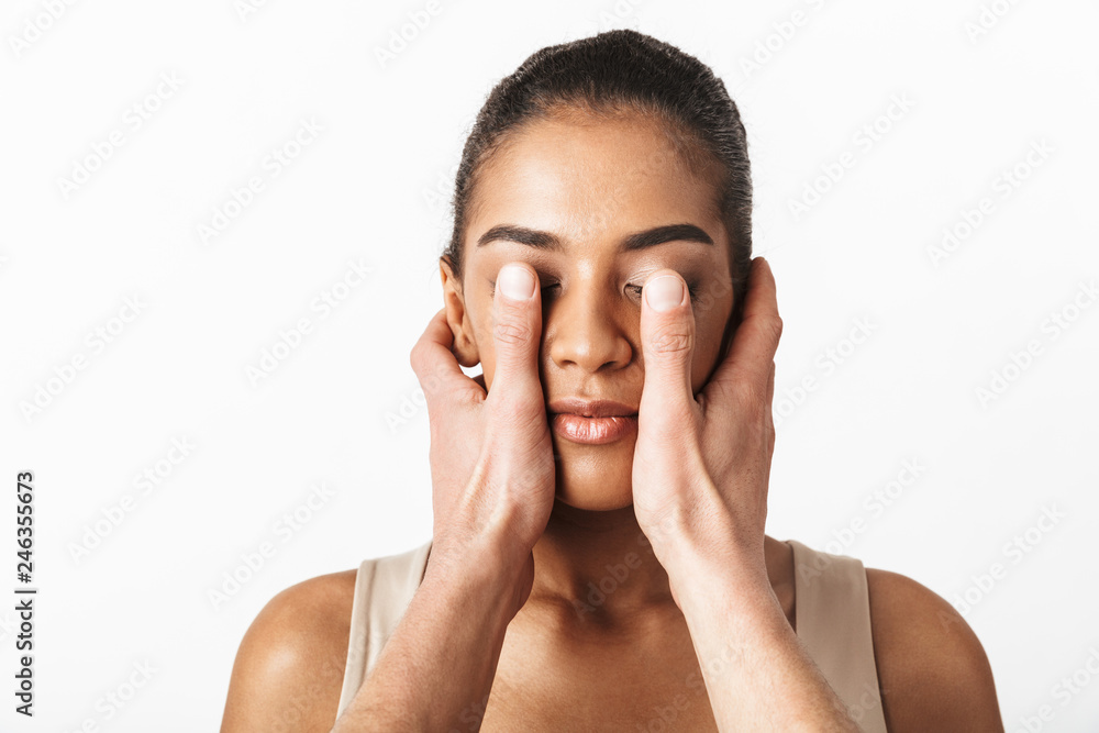 African woman posing isolated over white wall background while someone's hands covering her eyes. African woman posing isolated over white wall background while someone's hands covering her eyes.