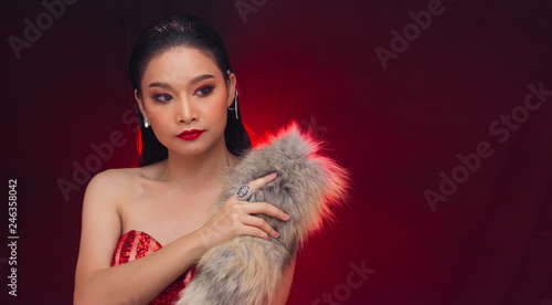Beautiful Young Asian black hair fur woman in fire red screen, high glitter fashion make up, studio lighting hot smoke burgundy background copy space, concept futuristic in heat empty space