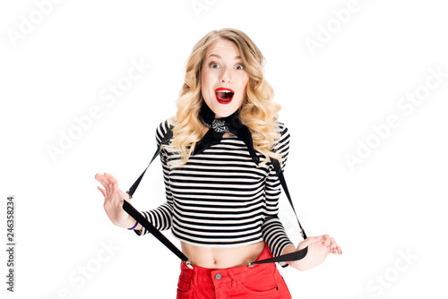 Photography surprised french woman with blonde hair holding suspenders isolated on white