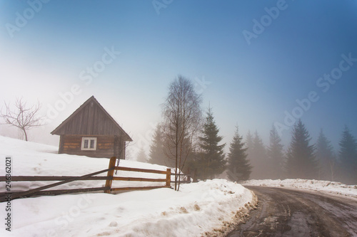 Fototapeta Naklejka Na Ścianę i Meble -  Lone house in mountain village. Foggy weather and melting snow